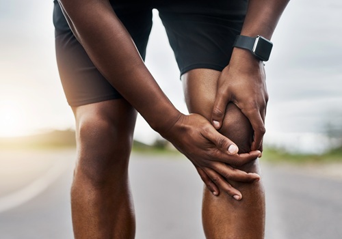 Nahaufnahme eines sportlichen Mannes, der beim Training im Freien an Knieschmerzen leidet