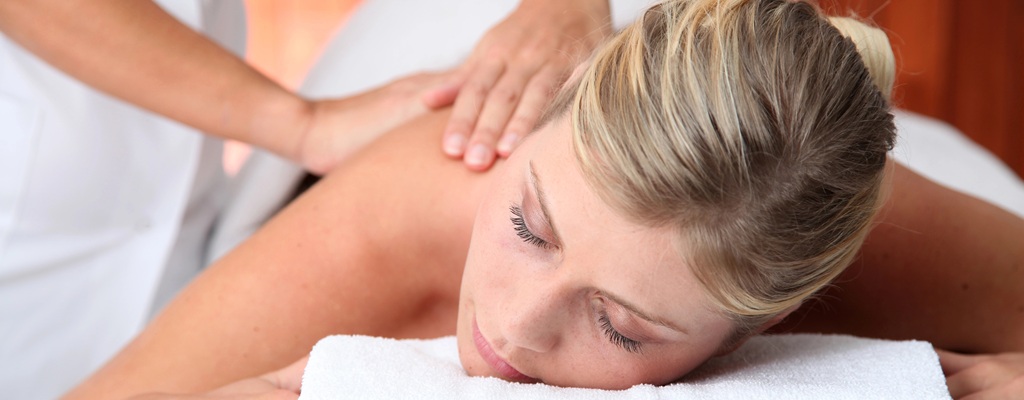 Frau in Bauchlage erhält eine sanfte Rückenmassage